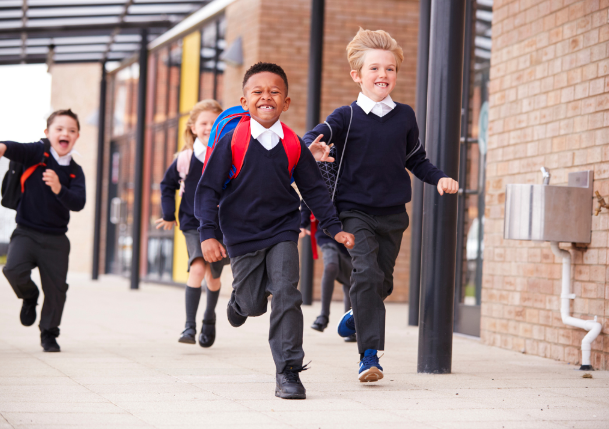 Primary school children running happily outside their school